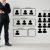 Businessman in suit standing beside a wall chart showing recruitment positions A to E and a group of target people icons