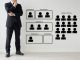 Businessman in suit standing beside a wall chart showing recruitment positions A to E and a group of target people icons